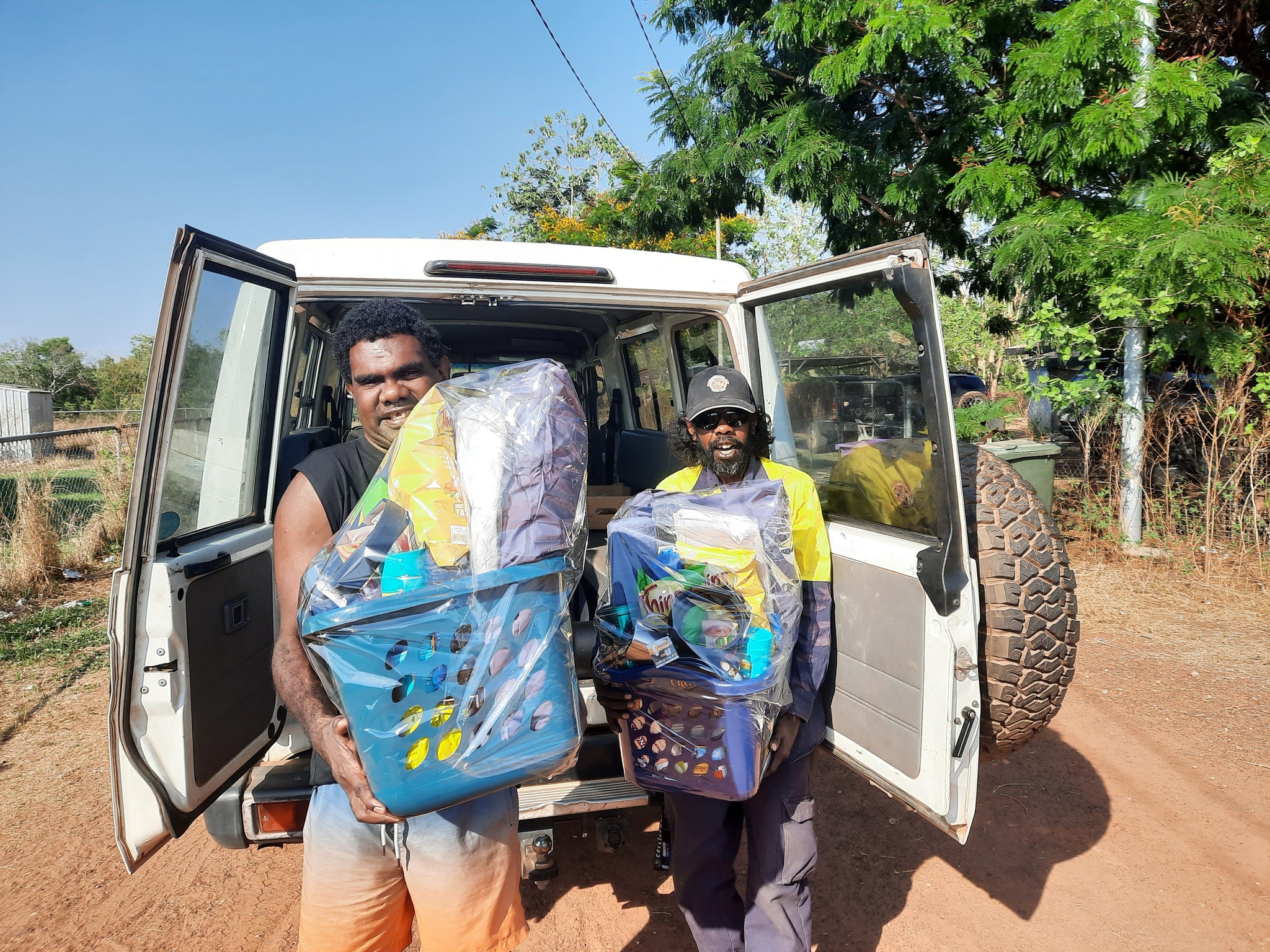 Two men smiling at the camera with large hampers in their hands