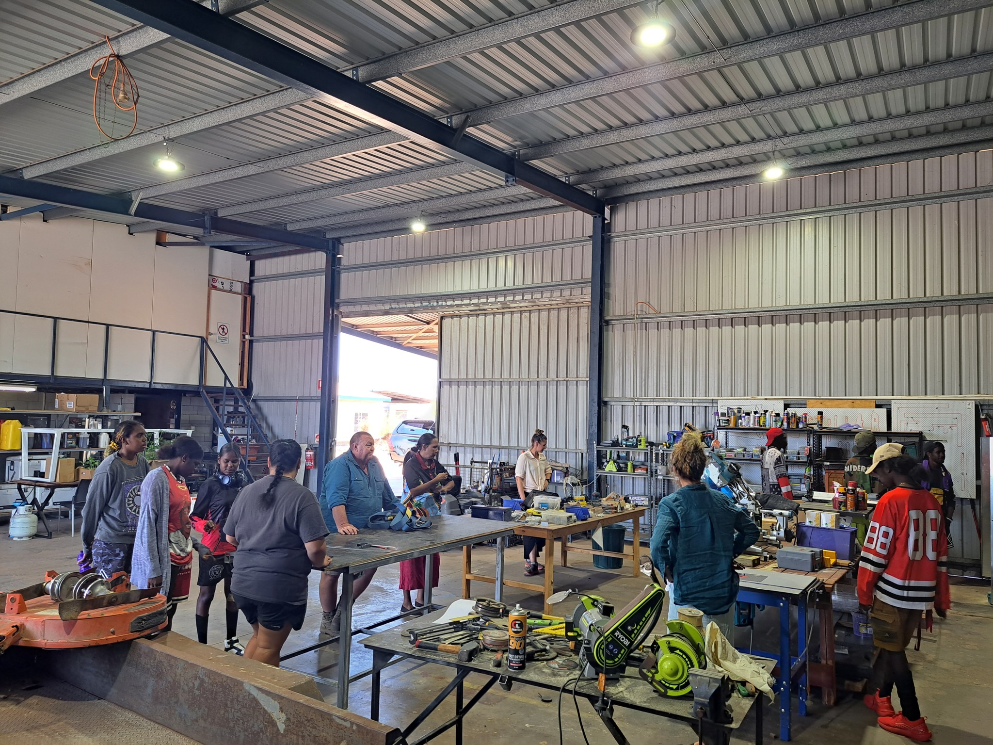 Picture of people walking around tables with PPE on them inside a warehouse